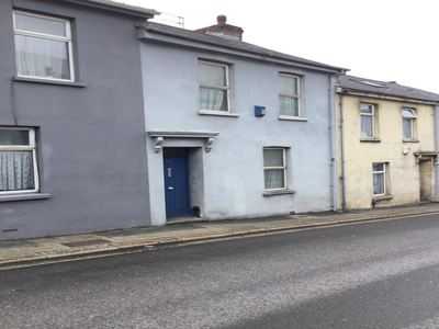 Light blue mid-terrace with a dark front door on a paved street