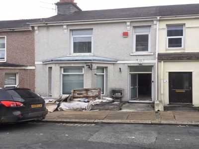 Rendered two-storey terrace with building materials stacked by the front door