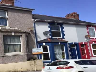 Grey-rendered terrace with a blue bay window on a residential street
